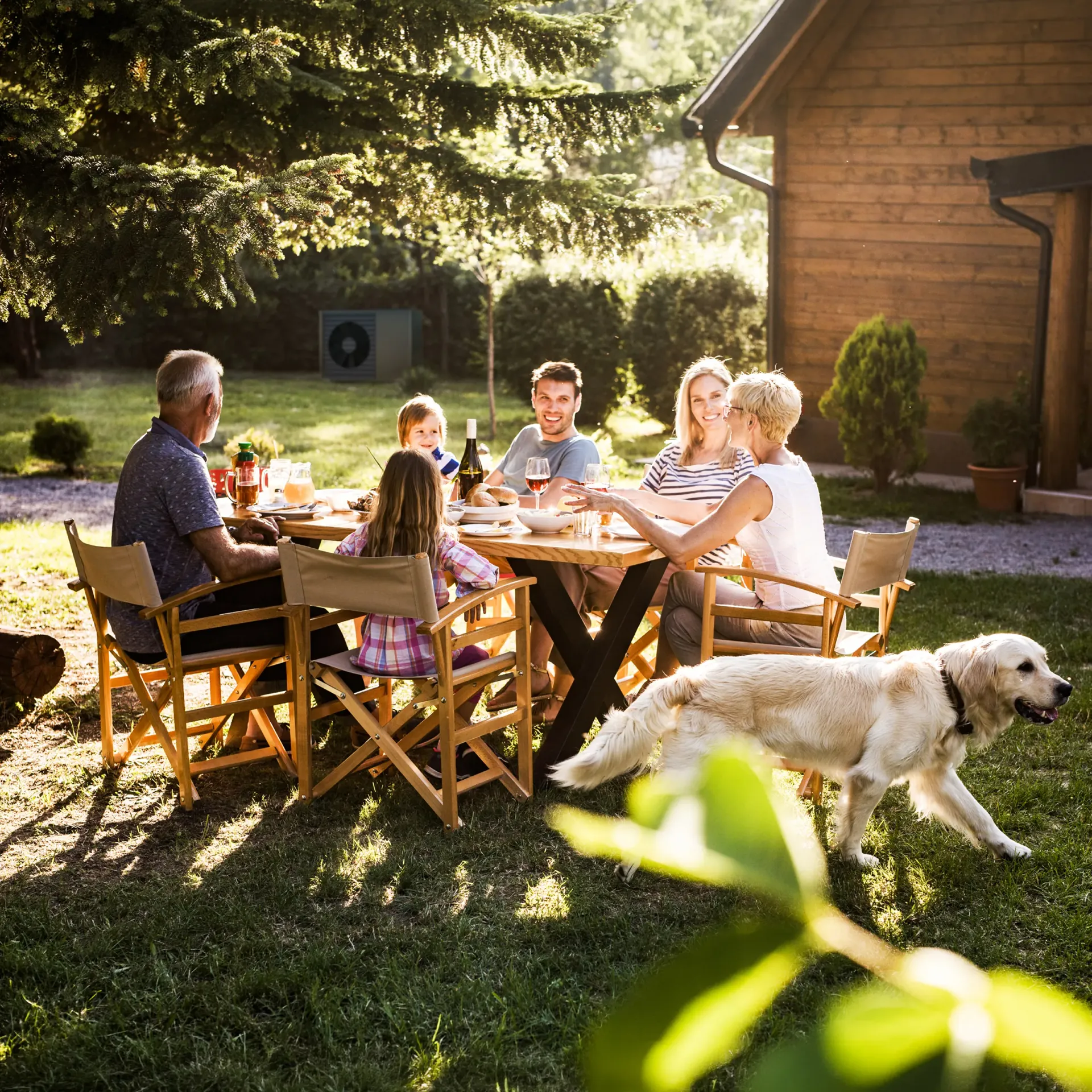 Familie am Gartentisch, Wärmepumpe im Hintergrund